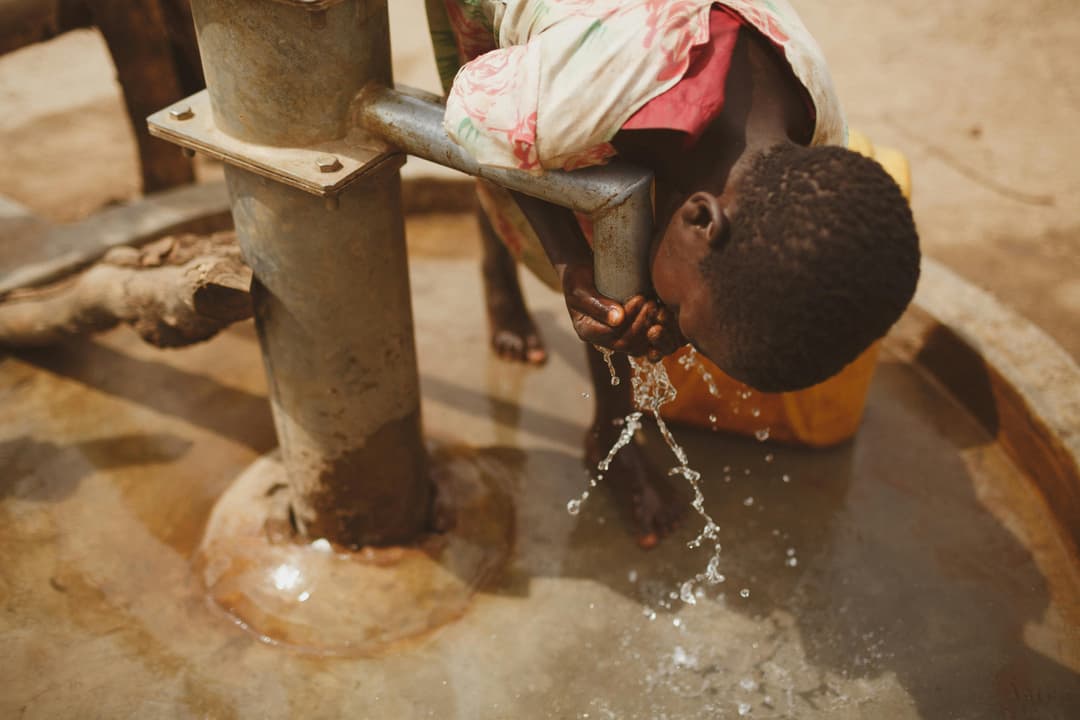 A child drinking from a bore hole